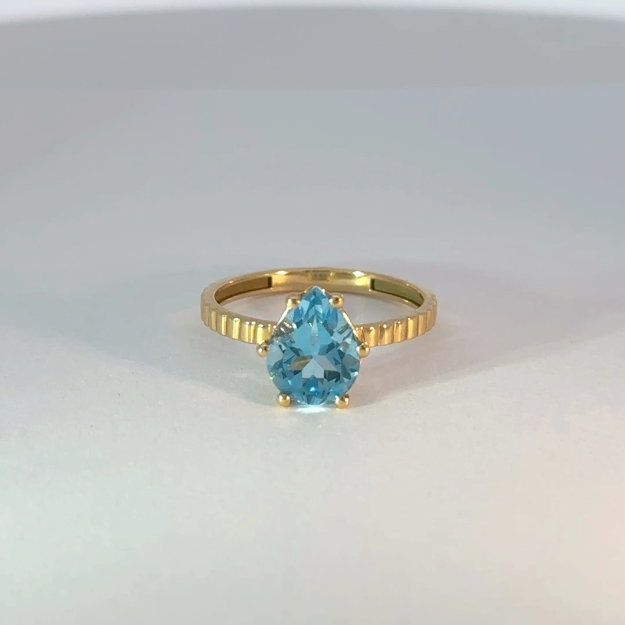Anillo solitario de oro con topacio azul en forma de pera